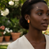Black model wearing coral-orange earrings in tranquil outdoor setting