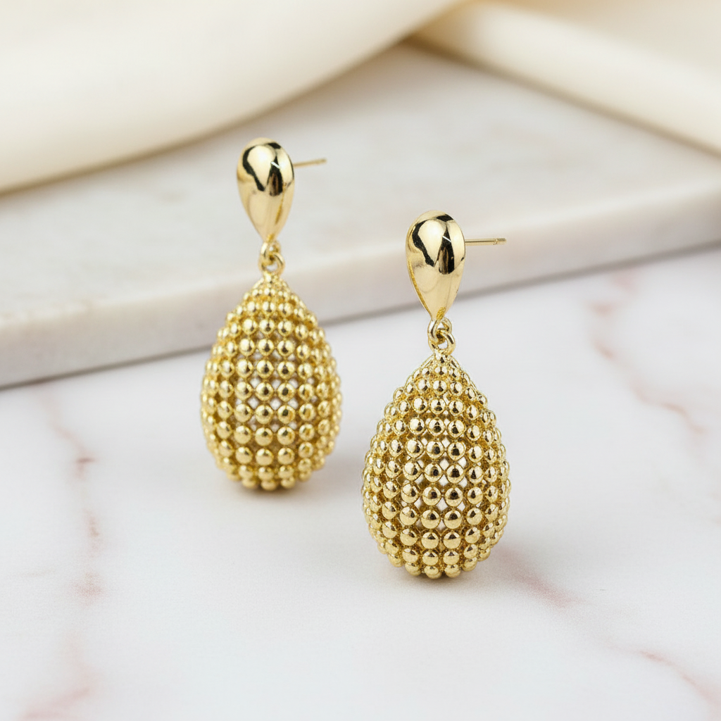 Gold droplet earrings on marble